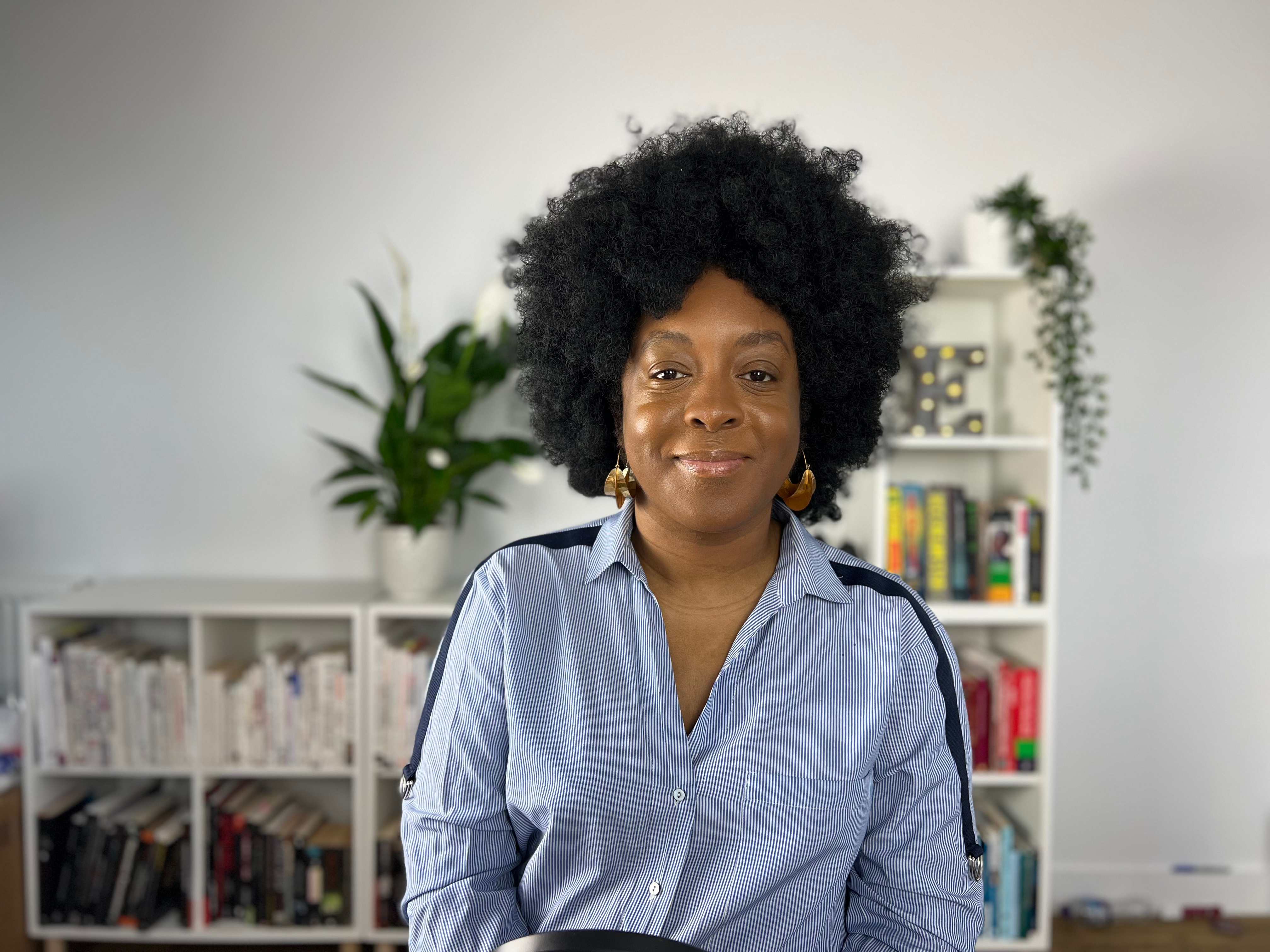 Professional portrait of a woman with curly hair in a modern office setting